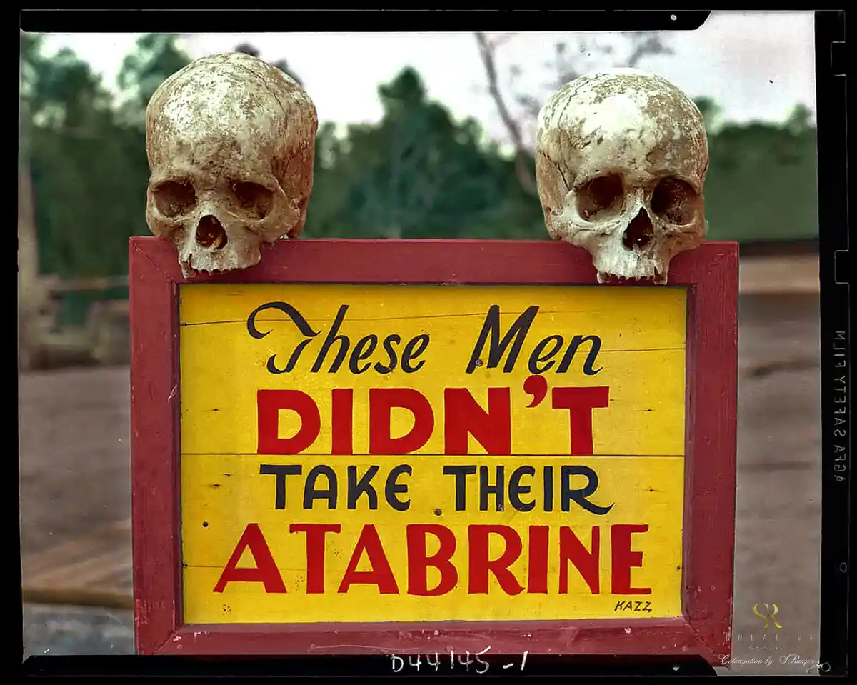 A yellow sign with a red border displays the text 'These Men DIDN'T TAKE THEIR ATABRINE' in black and red lettering, flanked…