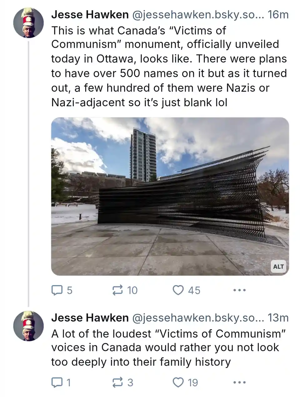 The image shows a large, modern, black metal monument with a wavy, layered design, situated outdoors on a concrete plaza…