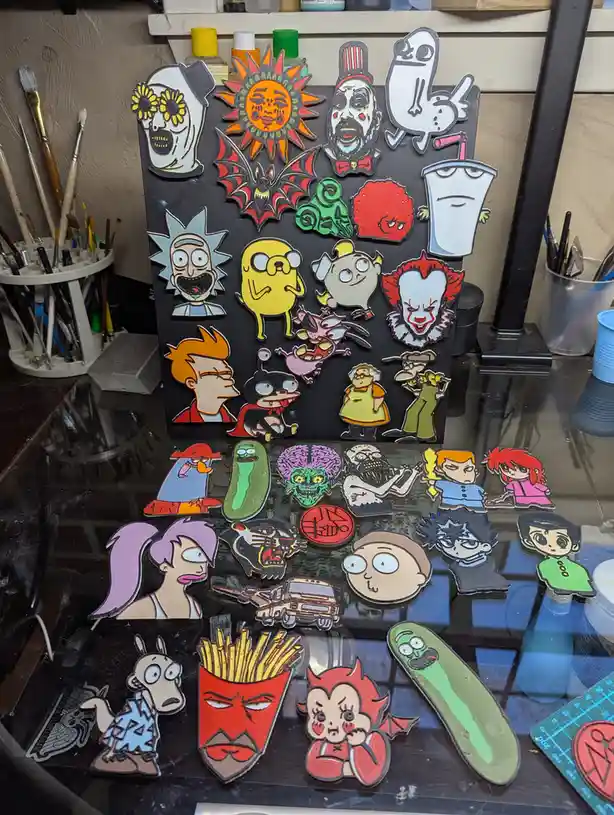A collection of colorful enamel pins featuring characters from various cartoons and pop culture, including Rick Sanchez…