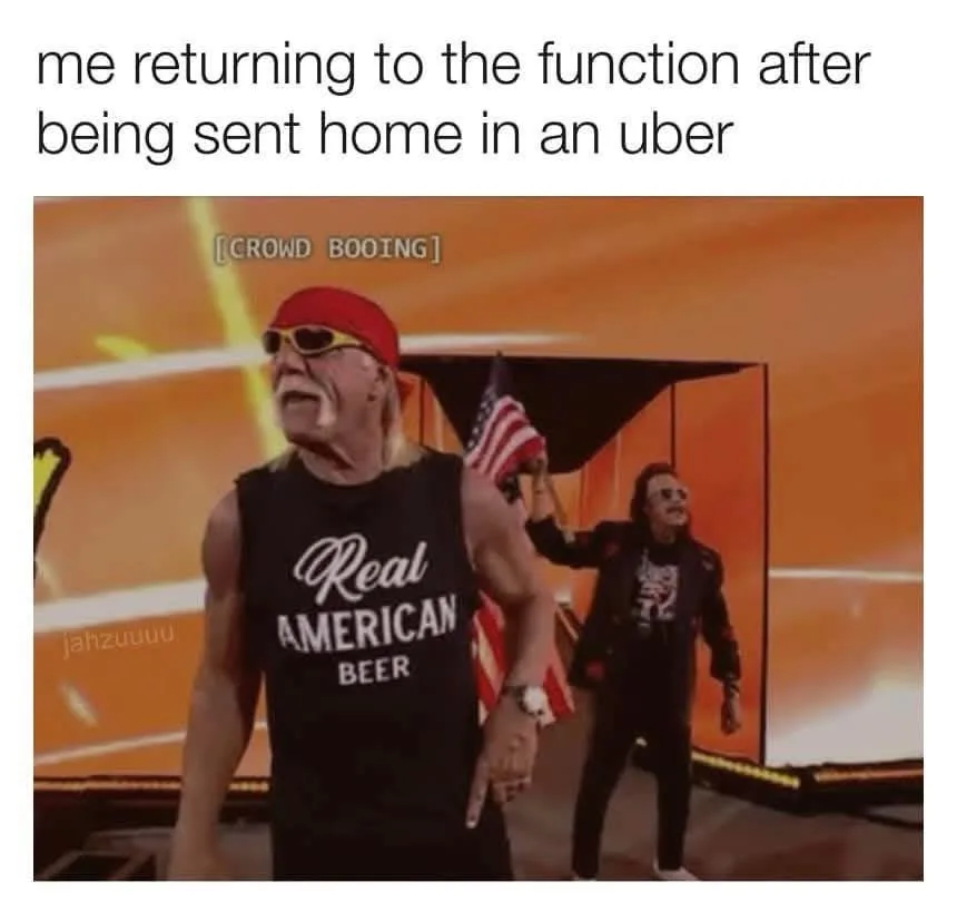 A muscular man with long blonde hair, wearing a red bandana, sunglasses, and a black tank top that says 'Real American…