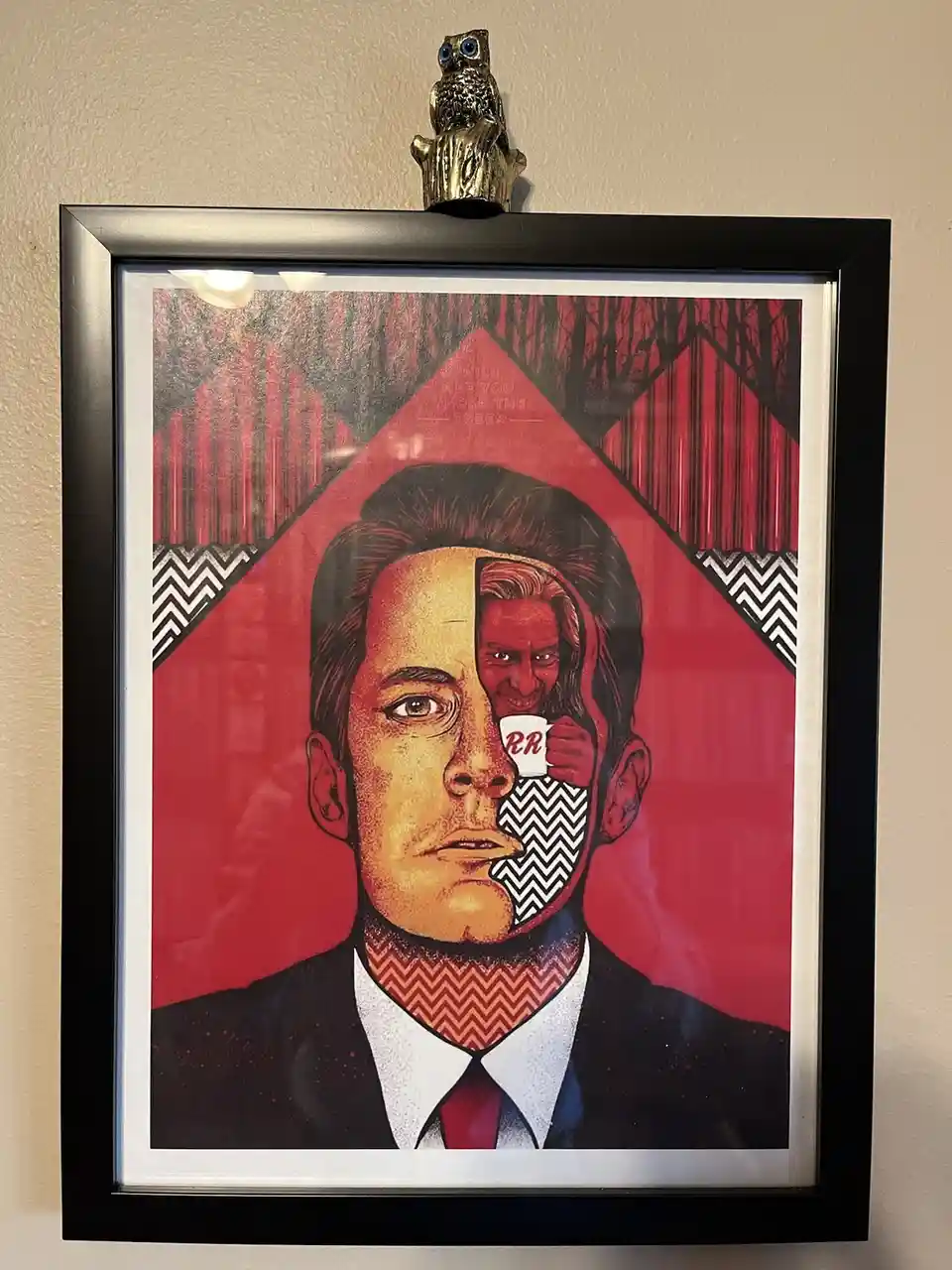 A framed pop art poster depicts a man in a suit with his face split down the middle; one side shows a calm expression, the…