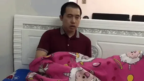A man sits on a bed under a pink blanket with cartoon sheep, looking confused. In the final frame, he pulls back the blanket…