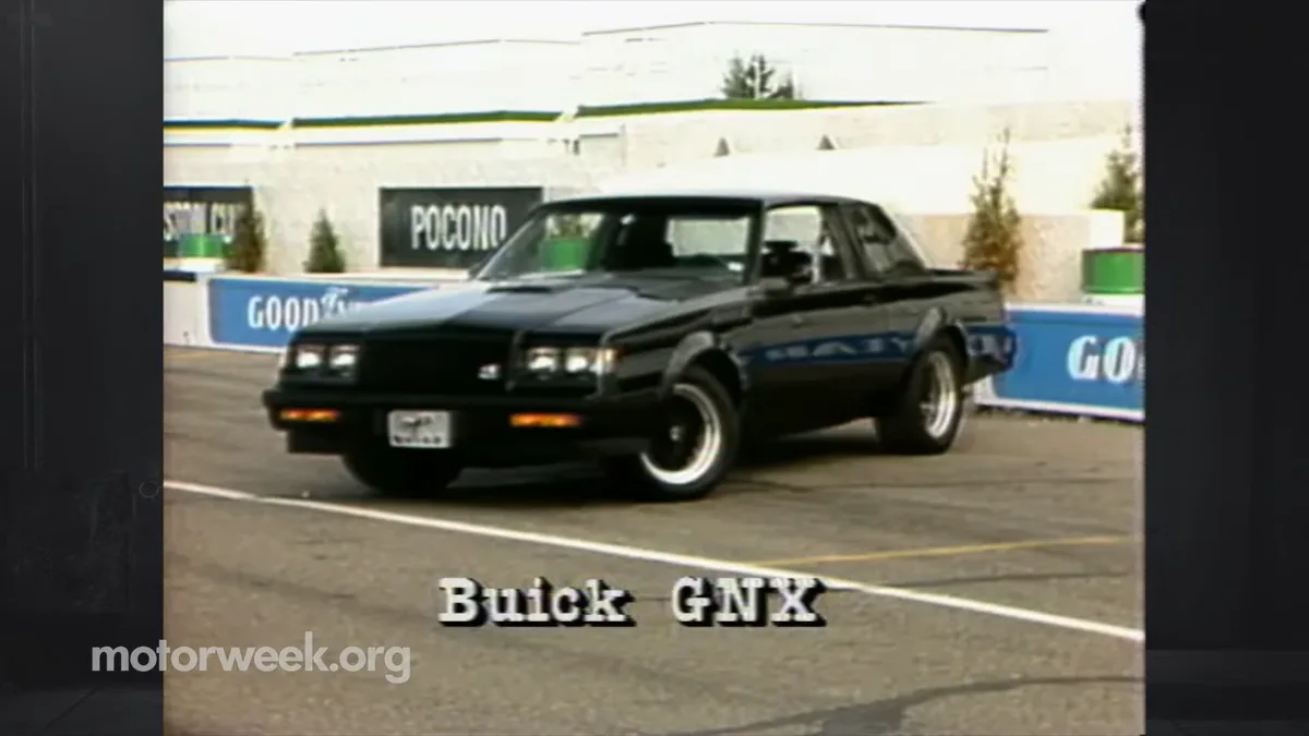 A black Buick GNX muscle car is shown driving on a racetrack with 'POCONO' and 'GOOD YEAR' signage visible in the…