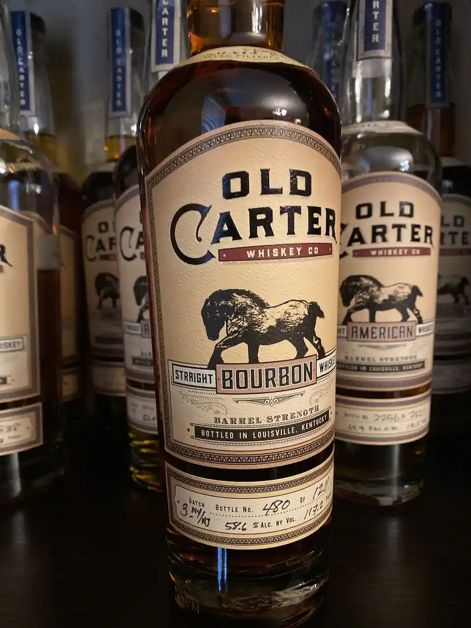 A close-up photograph shows a bottle of Old Carter Whiskey Co. Straight Bourbon, prominently displaying its label with a…