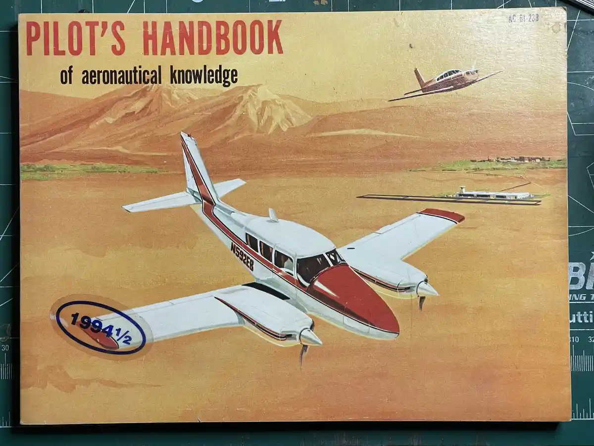 The image shows the cover of a 'Pilot's Handbook of Aeronautical Knowledge' with a vintage illustration of a white and red…