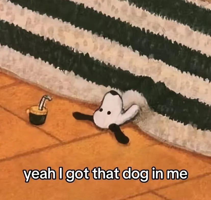 A plush toy dog with black ears and a black spot on its head is peeking out from under a black-and-white striped rug on a…