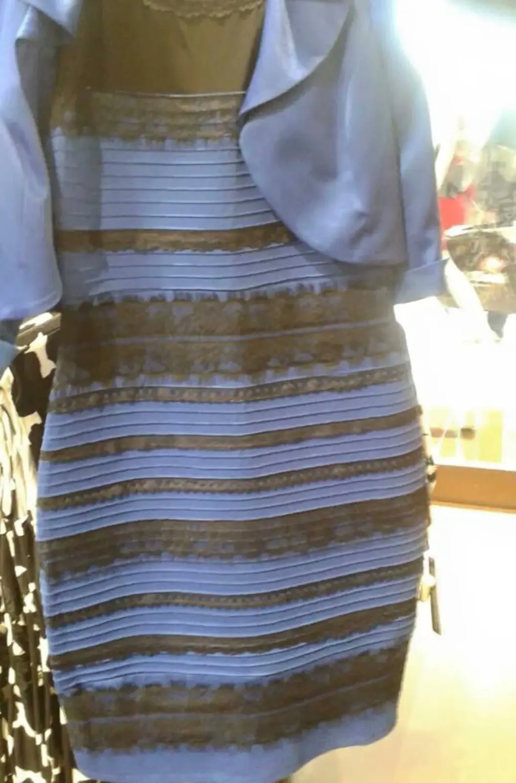 A close-up photo of a dress with alternating horizontal stripes that appear to be either blue and black or white and gold…