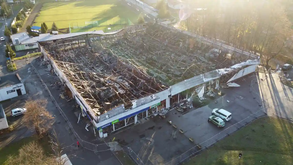An aerial photo shows a large commercial building with its roof and upper structure completely destroyed by fire, leaving…