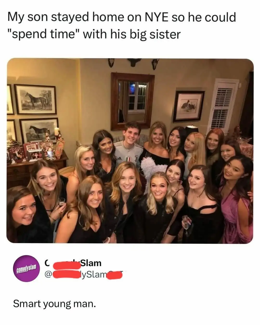 A group photo shows a young man surrounded by many smiling young women in a warmly lit room with framed pictures on the…