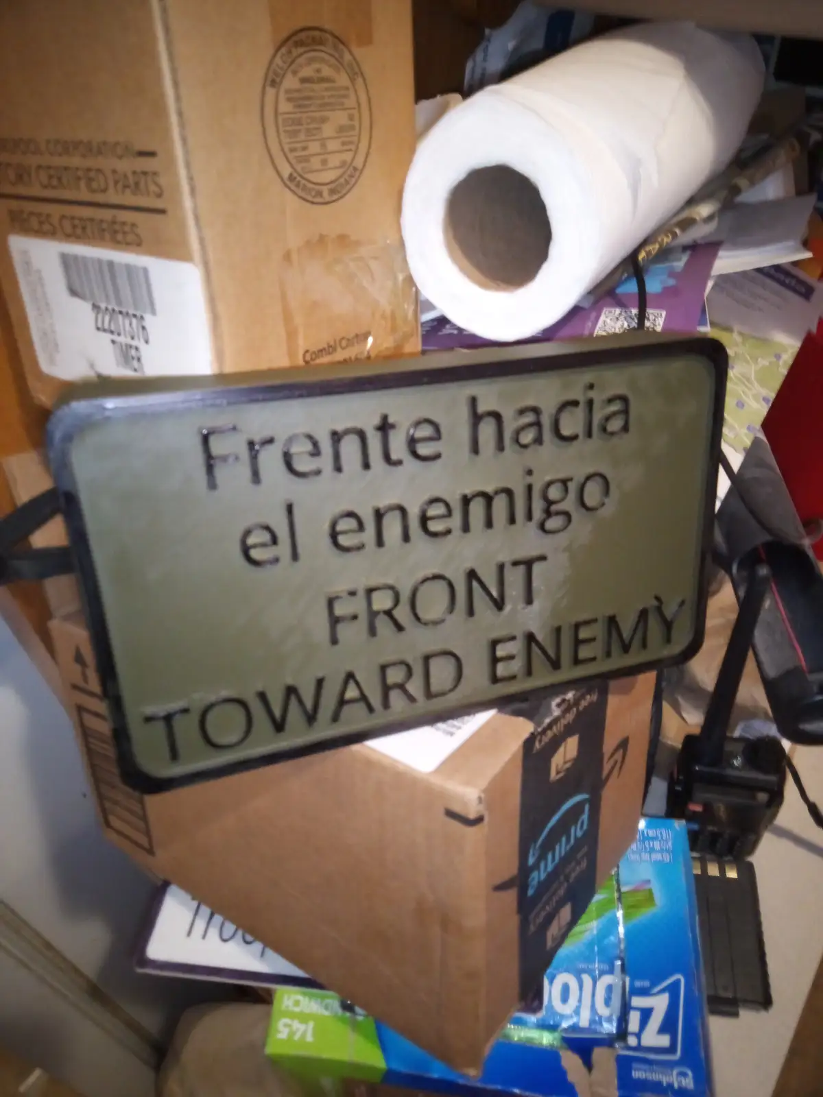A military-style directional sign reading 'Frente hacia el enemigo FRONT TOWARD ENEMY' in both Spanish and English is…