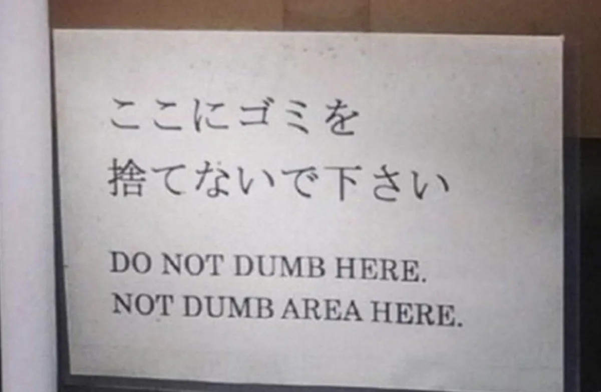 A white sign with Japanese text at the top and English text below, which reads 'DO NOT DUMB HERE. NOT DUMB AREA HERE.' The…