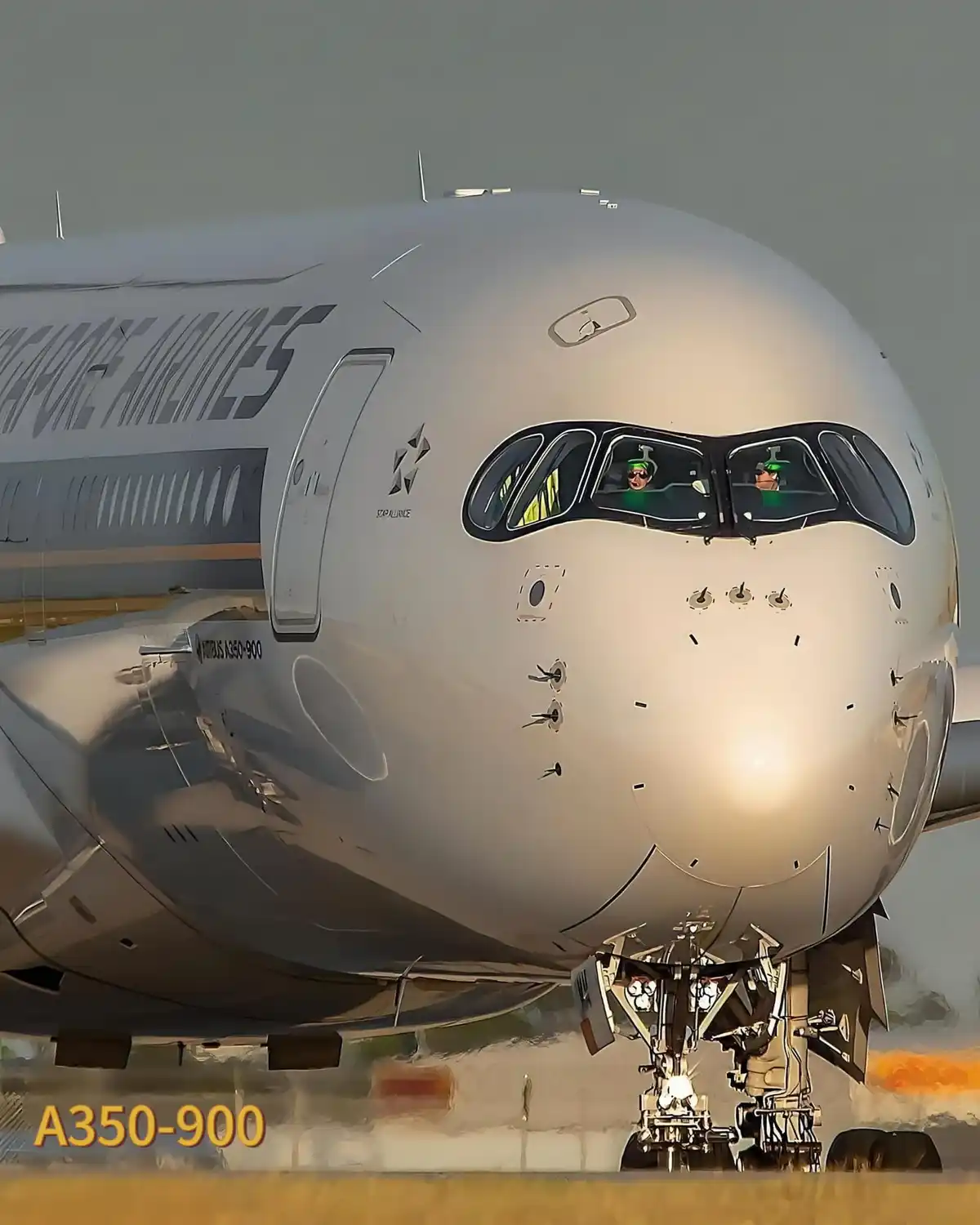 A close-up frontal view of a Singapore Airlines Airbus A350-900 aircraft on the tarmac, with the cockpit windows showing two…