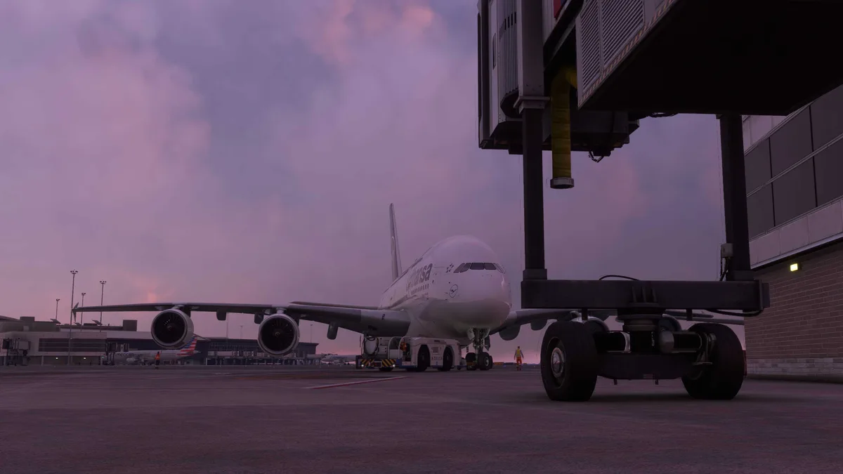 A low-angle shot of a large white Airbus A380 airplane parked at an airport gate under a purple twilight sky. The plane's…