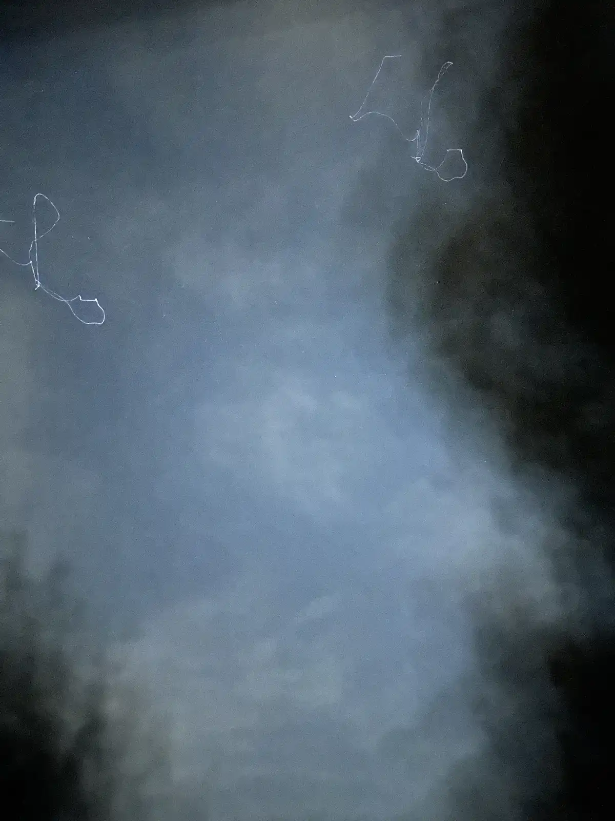 A dark, cloudy sky with faint white chalk-like scribbles resembling abstract figures or letters in the upper corners. The…