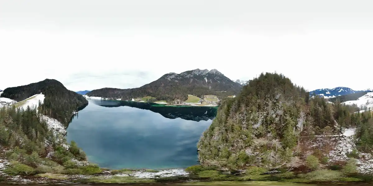 A panoramic 360-degree view of a serene alpine lake surrounded by snow-dusted evergreen forests and distant mountains under…