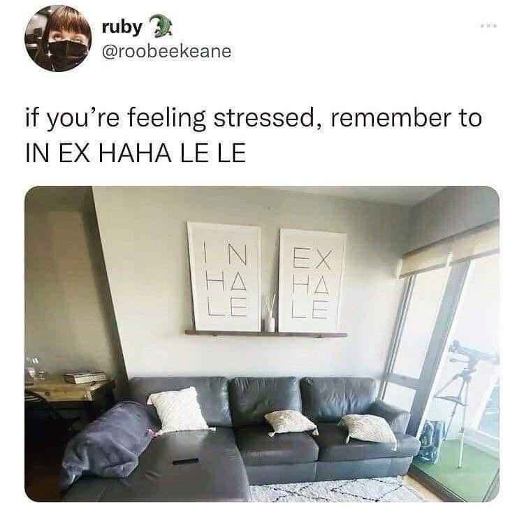 A photo of a living room with a black leather couch and two framed wall art pieces above it that read 'INHALE' and 'EXHALE'…