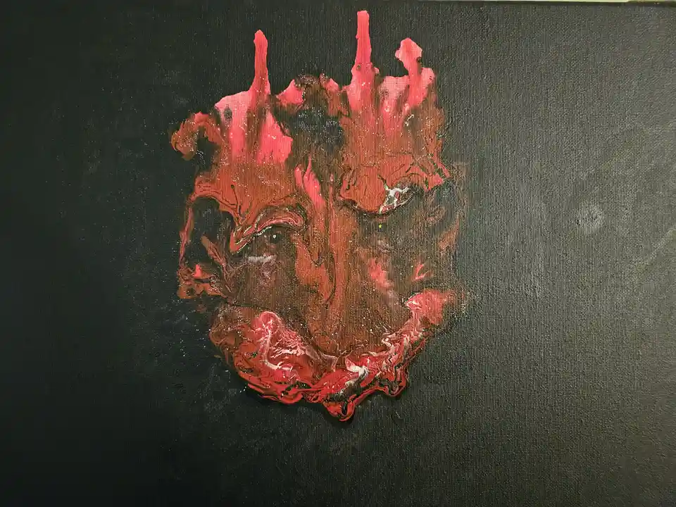 A painting on black canvas depicts a stylized, abstract bulldog face made of red, brown, and white paint with a textured…