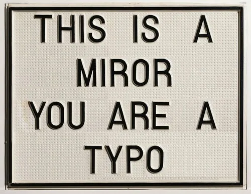 A white lightbox sign with black letter tiles displays the text 'THIS IS A MIROR YOU ARE A TYPO', where 'MIROR' is a…