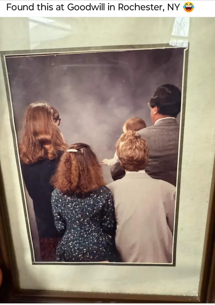 A framed, vintage family photograph showing the backs of four adults and a baby, all looking toward the right side of the…