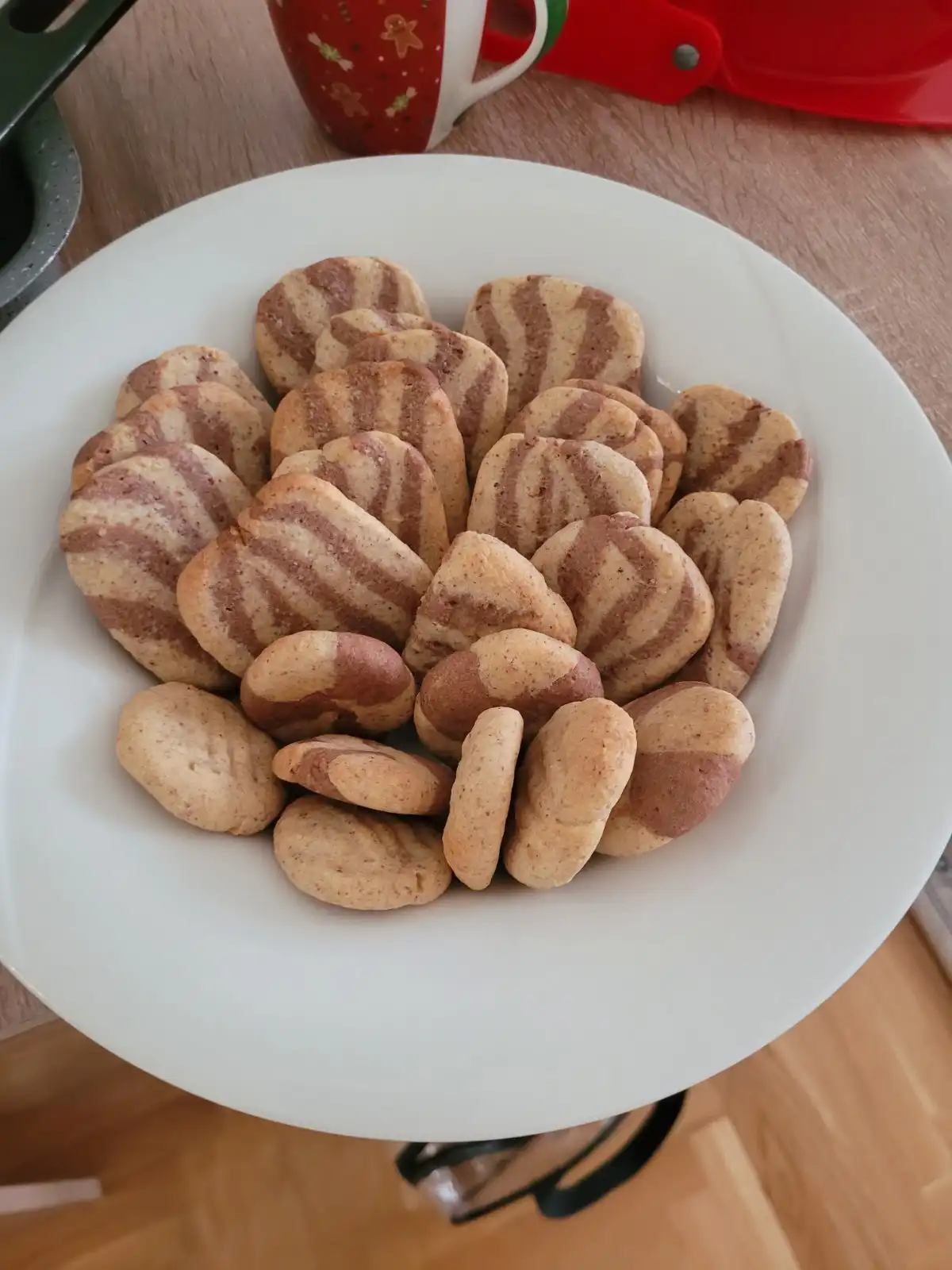 A white plate holds two types of cookies: some with brown and beige zebra-like stripes, others with a solid brown half and…