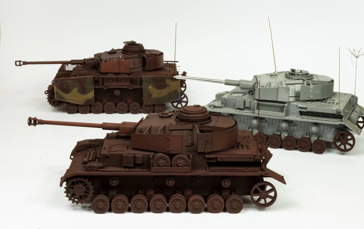 Three model tanks are shown against a white background; two are brown and one is grey. The grey tank has a long barrel and…