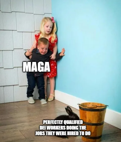A young girl in a red dress stands behind a crying toddler boy, both positioned in a corner with a wooden bucket and a black…