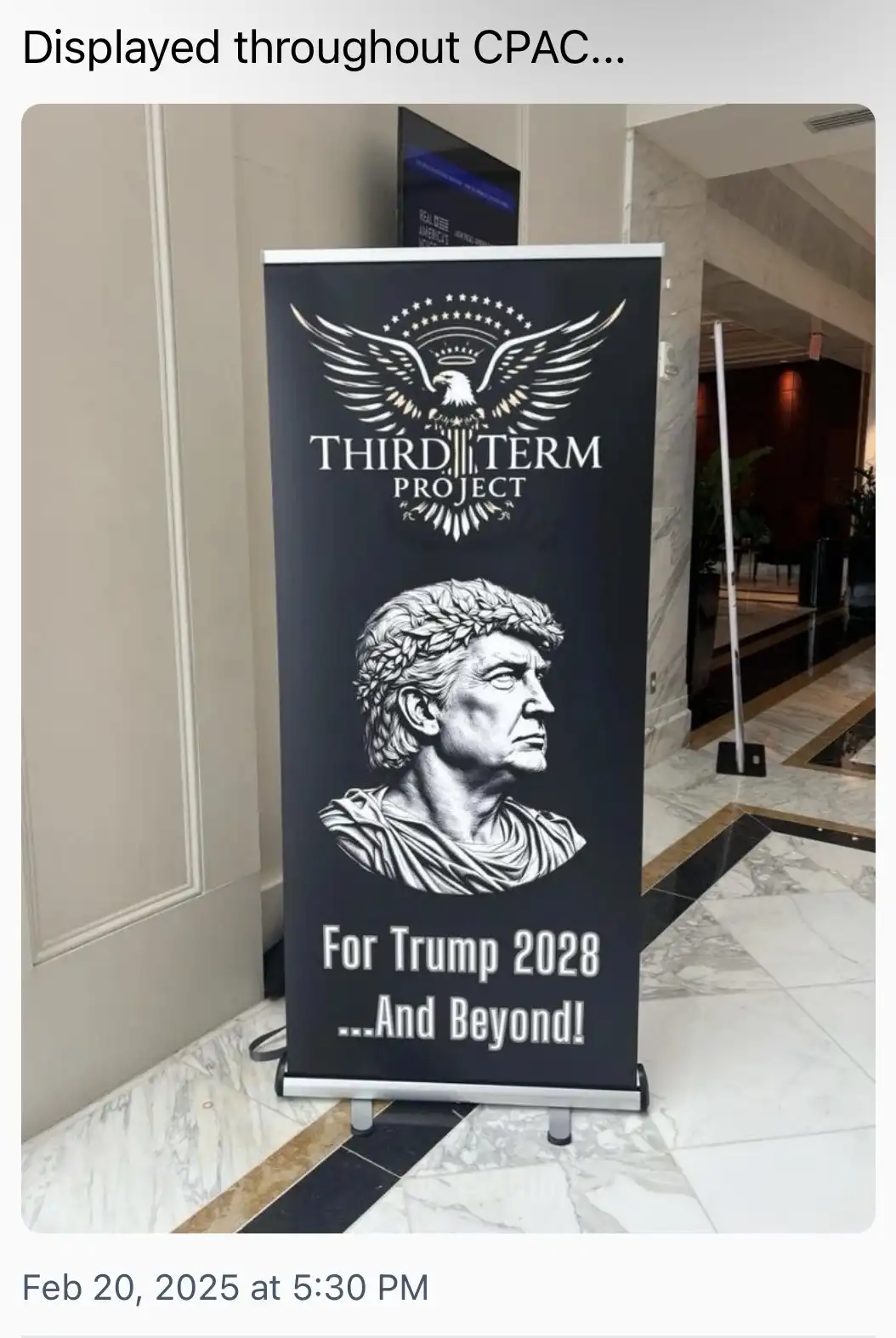A black banner standee at a convention displays a logo of an eagle with stars above the text 'THIRD TERM PROJECT'. Below, a…