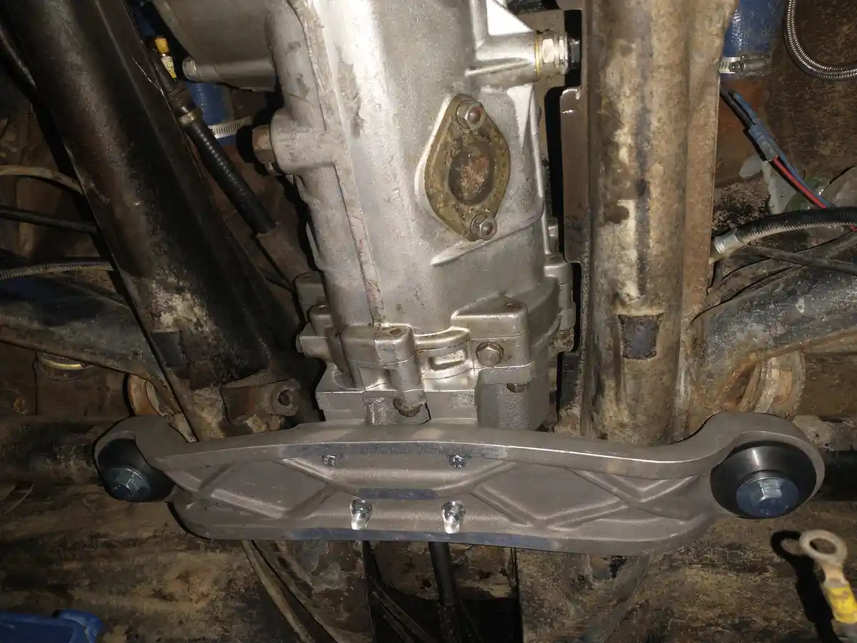 A close-up photo of a vehicle's undercarriage showing a newly installed control arm bolted to the chassis, surrounded by…