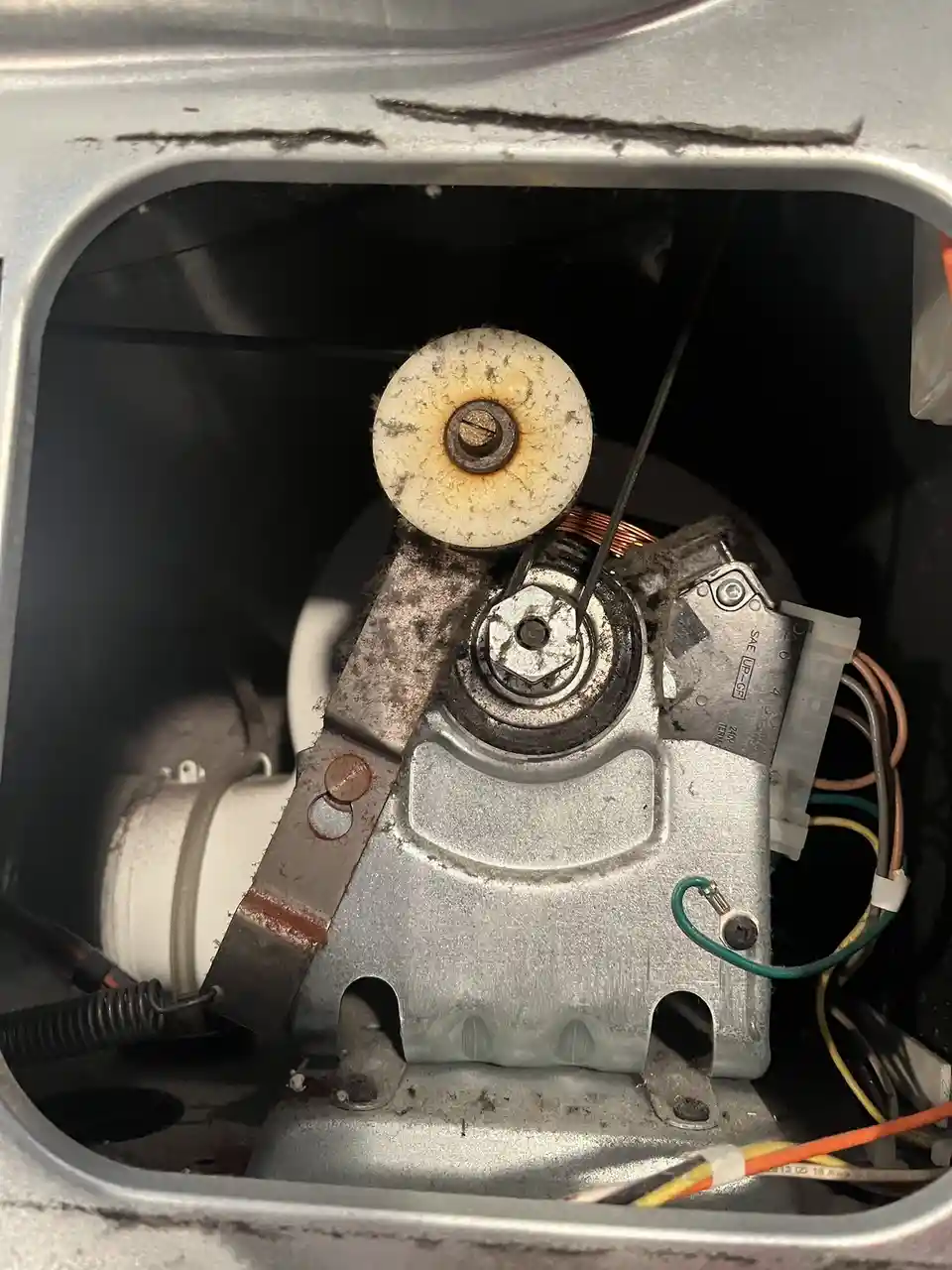A close-up photo shows the interior of a dryer with a dirty, lint-covered motor and pulley assembly. The image is overlaid…
