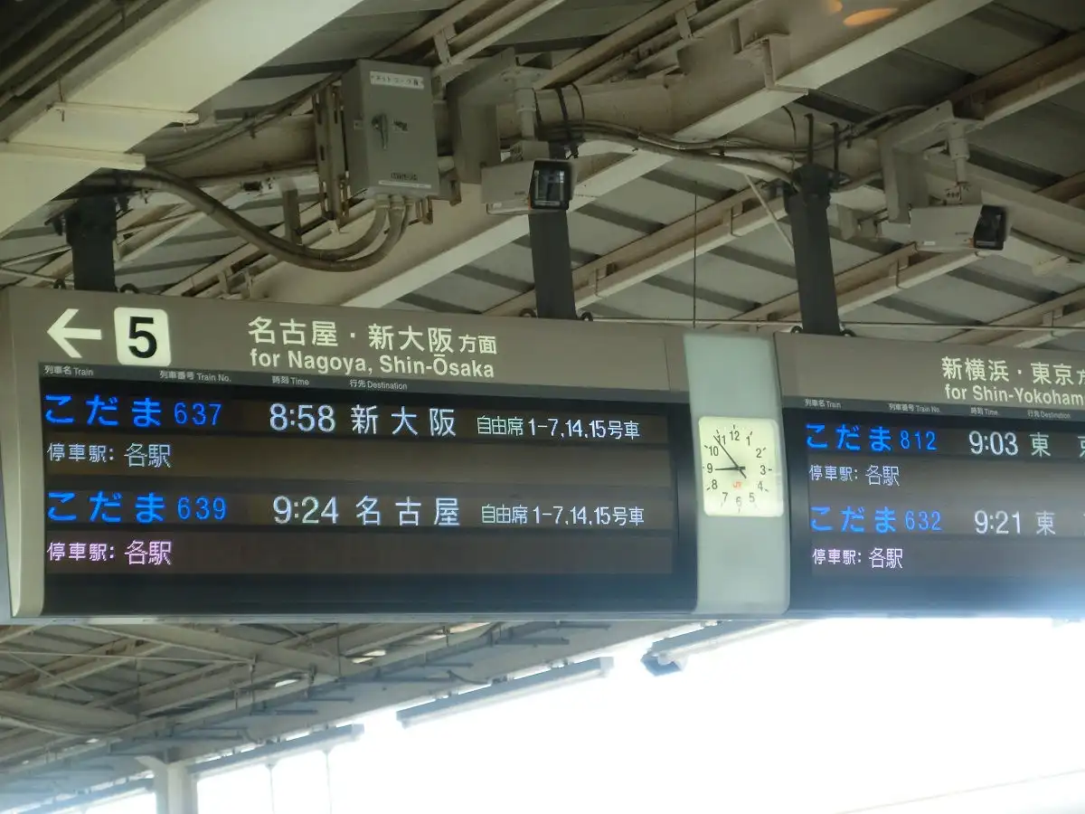 A photo of a Japanese train station platform sign showing train information for platform 5, with a digital clock displaying…