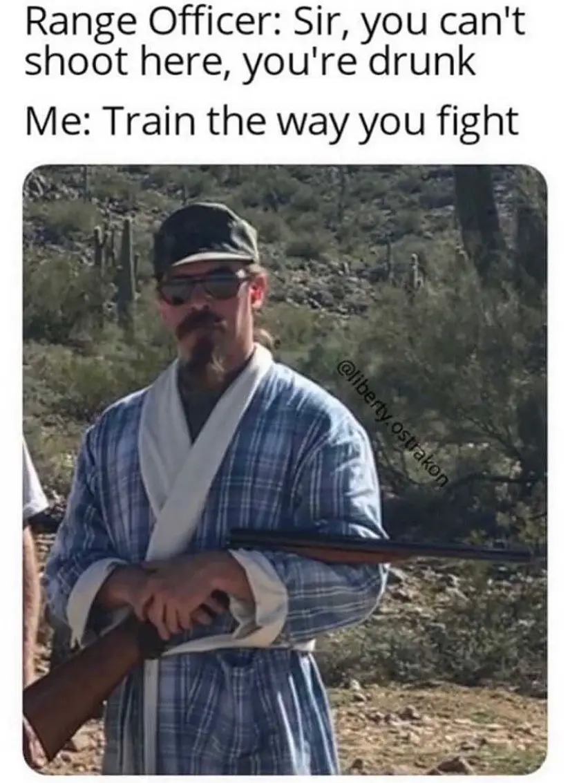 A man with a mustache and sunglasses, wearing a blue plaid robe and a cap, holds a rifle in a desert setting with cacti and…