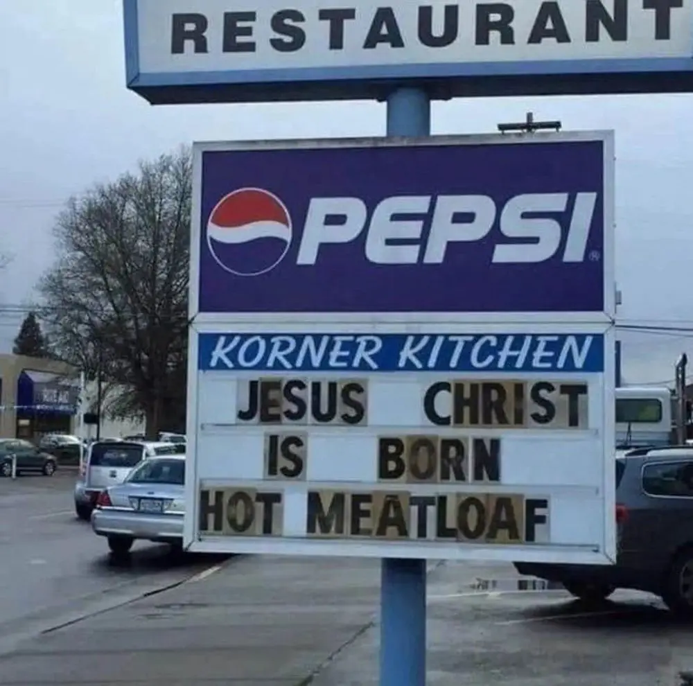 A restaurant sign for 'Korner Kitchen' features a Pepsi logo above a marquee board that reads 'JESUS CHRIST IS BORN HOT…
