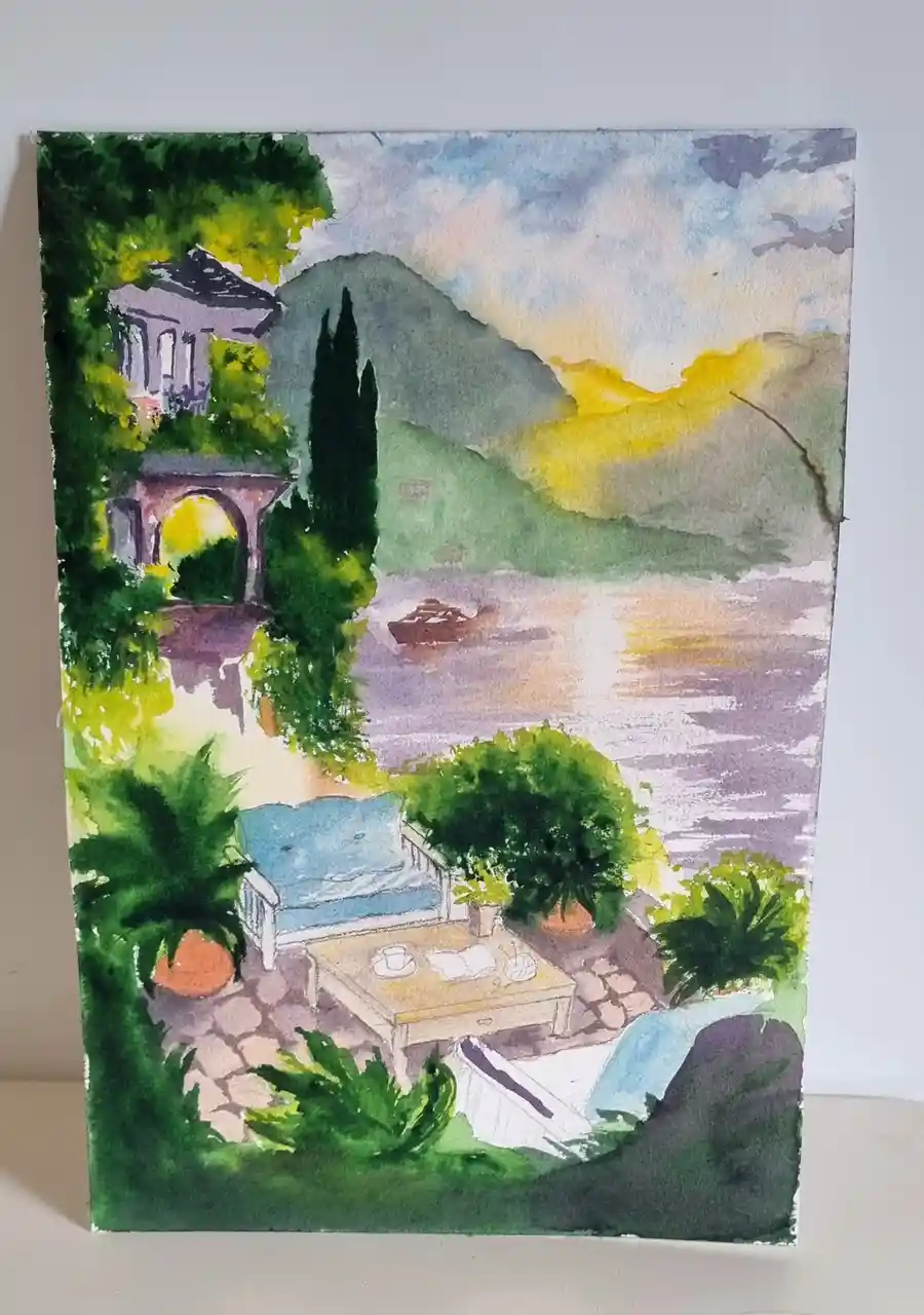 A watercolor painting depicts a serene lakeside patio with a blue sofa, coffee table with a cup and book, and lush greenery…
