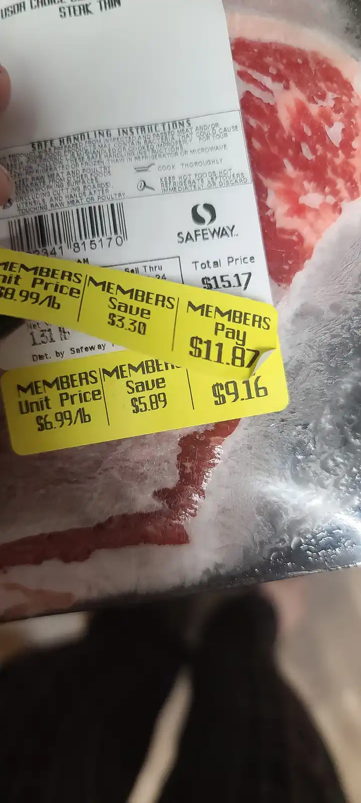 A close-up photo of a package of frozen steak from Safeway, showing two overlapping yellow price tags for members. The top…