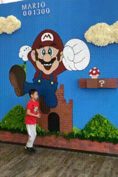 A sequence of images shows a young boy in a red shirt and white pants interacting with a large, three-dimensional…