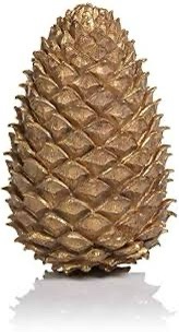 a close-up photograph of a large, ornamental pinecone with a metallic gold finish, standing upright on a reflective white…