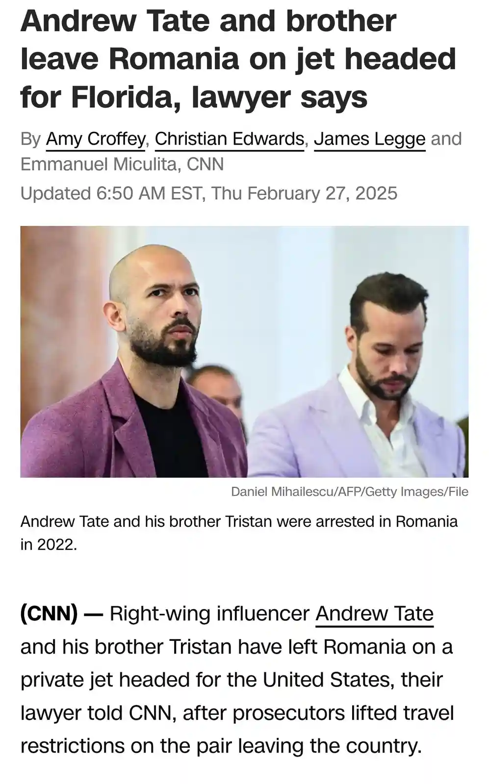 The image shows two men, Andrew Tate (left, in a purple blazer) and his brother Tristan (right, in a light purple blazer)…
