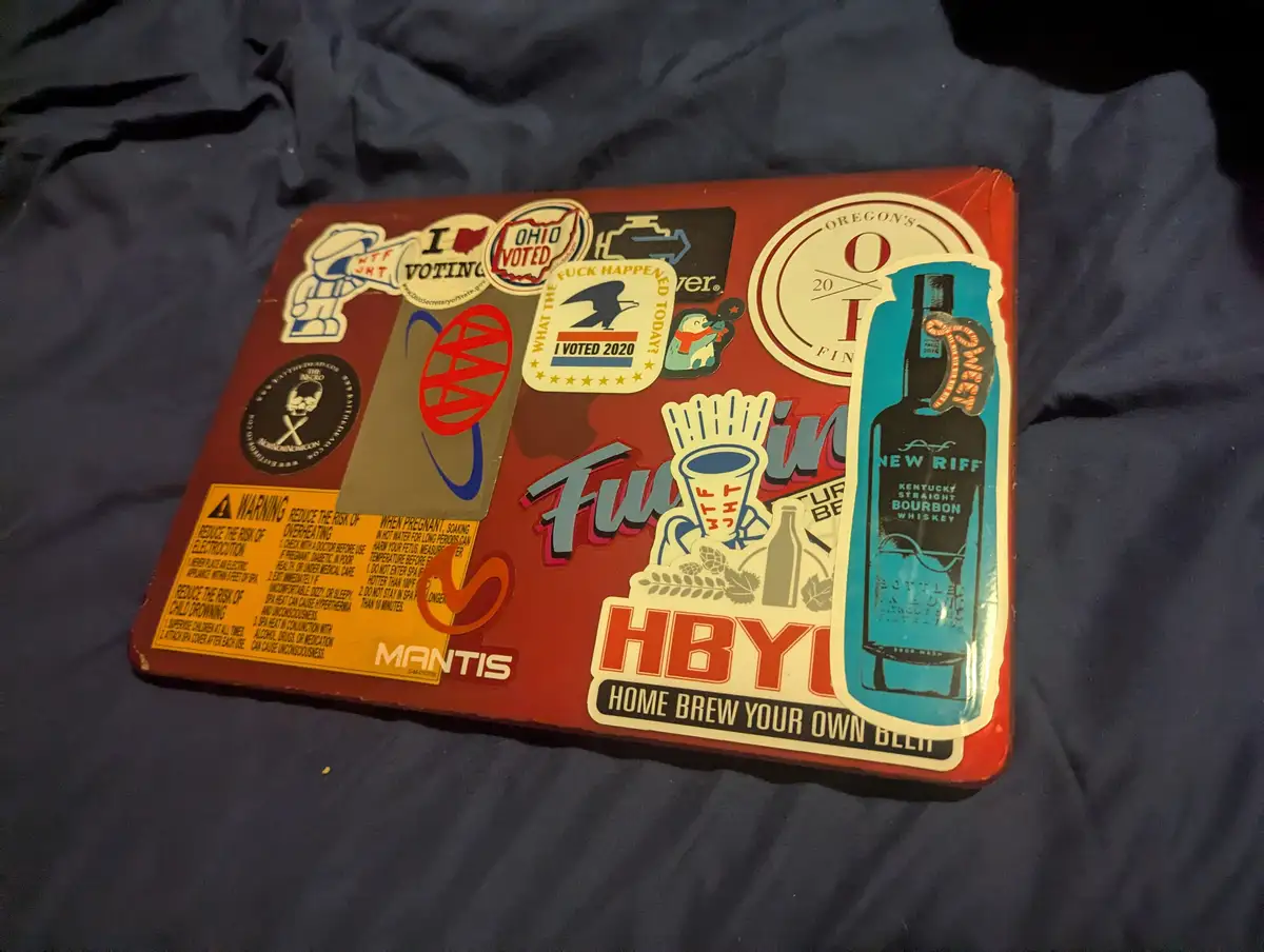 A red metal tray covered in various stickers, including 'I Voted 2020', 'What the Fuck Happened Today?', 'Ohio Voted', 'Home…