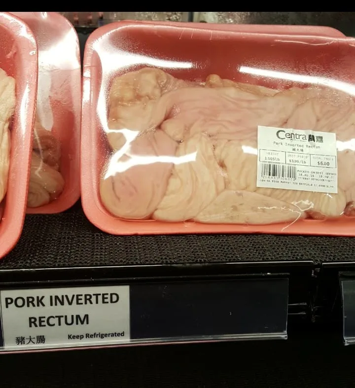 A supermarket meat display shows a pink plastic tray containing raw, pale pink, wrinkled pork intestines, labeled 'Pork…