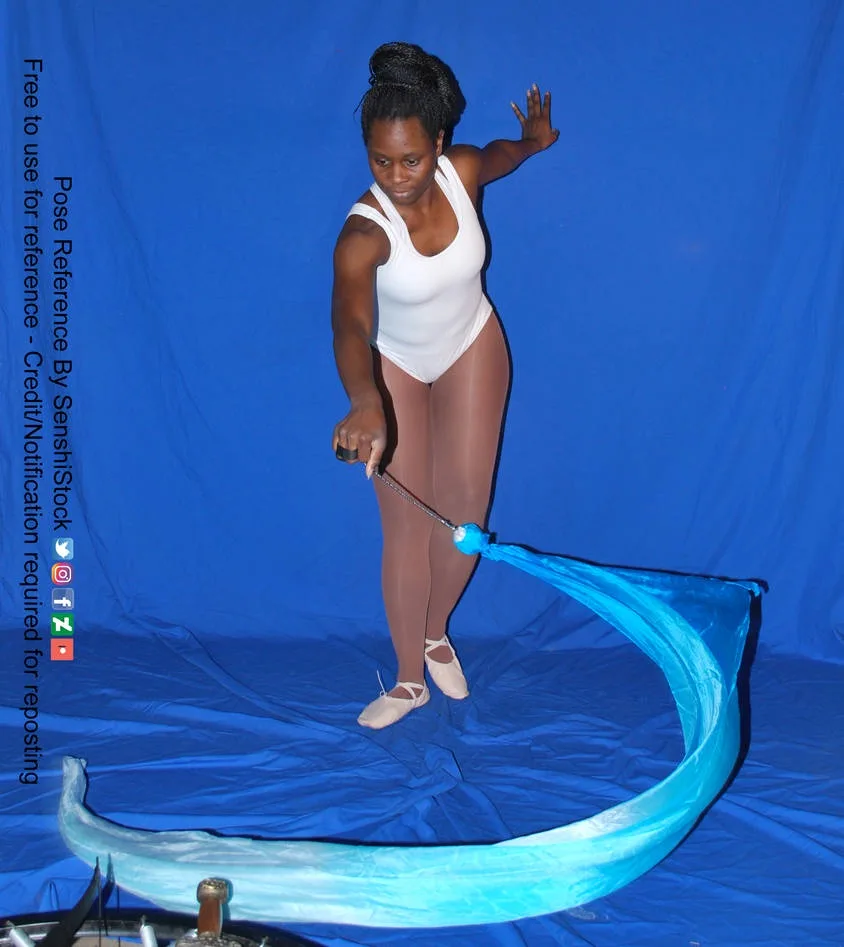 A woman in a white leotard and beige tights stands on a blue backdrop, holding a blue ribbon that flows in a wide arc around…