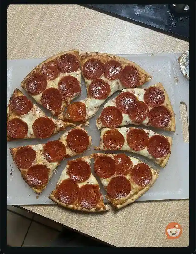 A pepperoni pizza is sliced into eight pieces and arranged on a white cutting board, with one slice noticeably smaller and…
