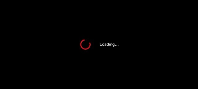 A black screen with a red, incomplete circular loading icon centered, accompanied by the white text 'Loading...' to its…