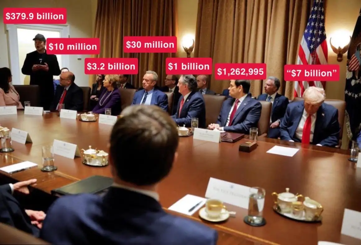 A photo of a formal meeting with several people seated around a large wooden table, including a man standing at the head…