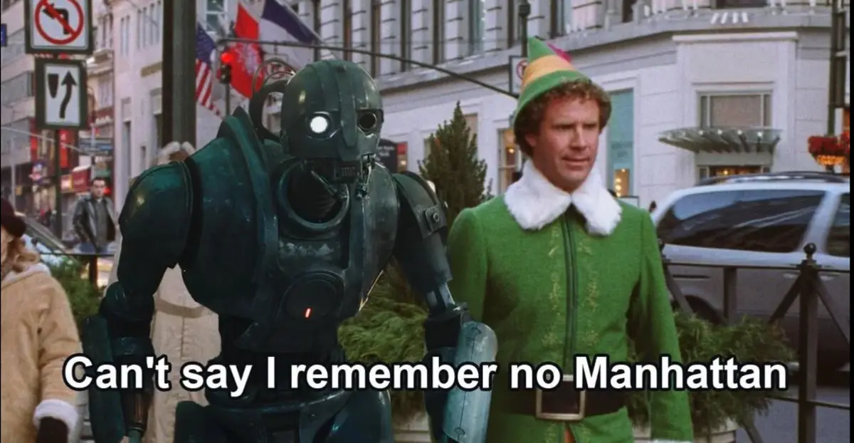 A green robot with a glowing white eye and a human-like face stands next to a man in a green elf costume with a pointed hat…