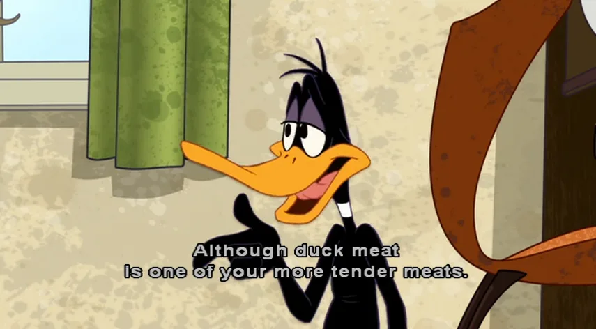 A cartoon duck with a long orange beak and black feathers, wearing a black suit, gestures with both hands while speaking…