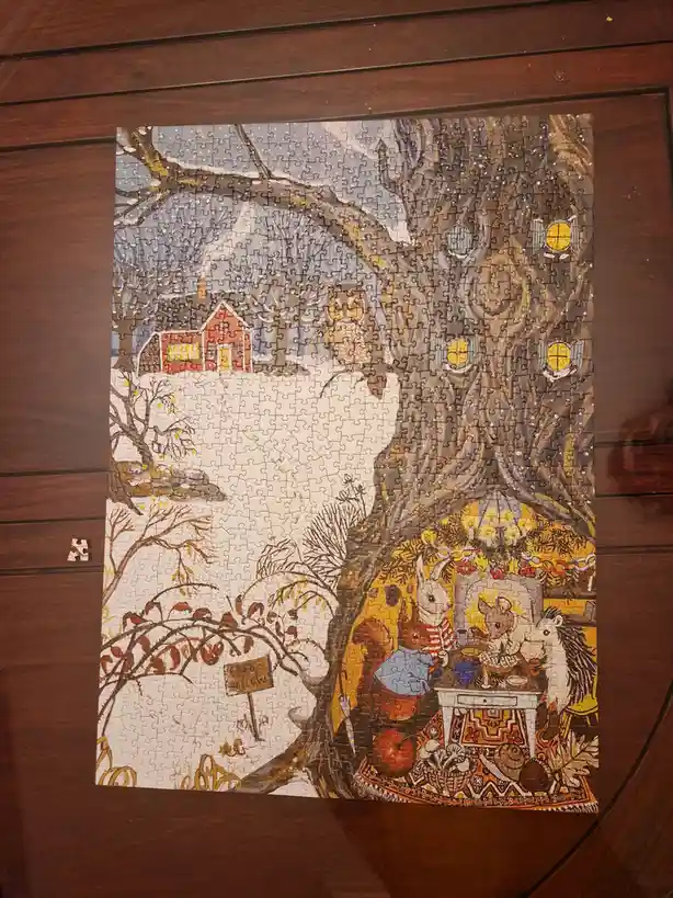 A completed jigsaw puzzle depicts a cozy winter scene with anthropomorphic animals gathered around a table inside a hollow…