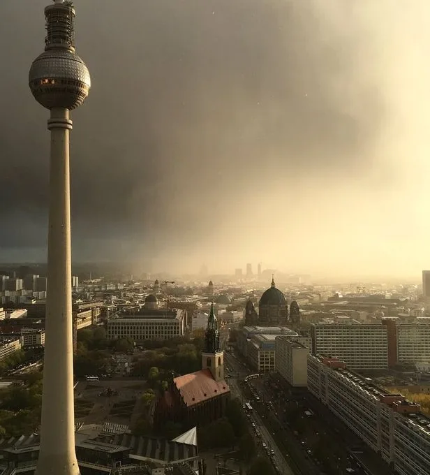 A dramatic cityscape photo of Berlin, featuring the iconic Fernsehturm tower on the left and the Berlin Cathedral in the…