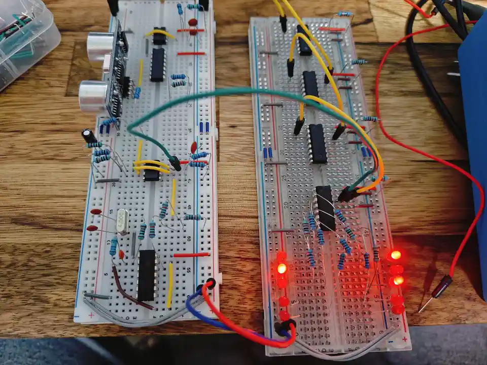 Two breadboard circuits sit side-by-side on a wooden table; the left one has no lights on, while the right one has multiple…