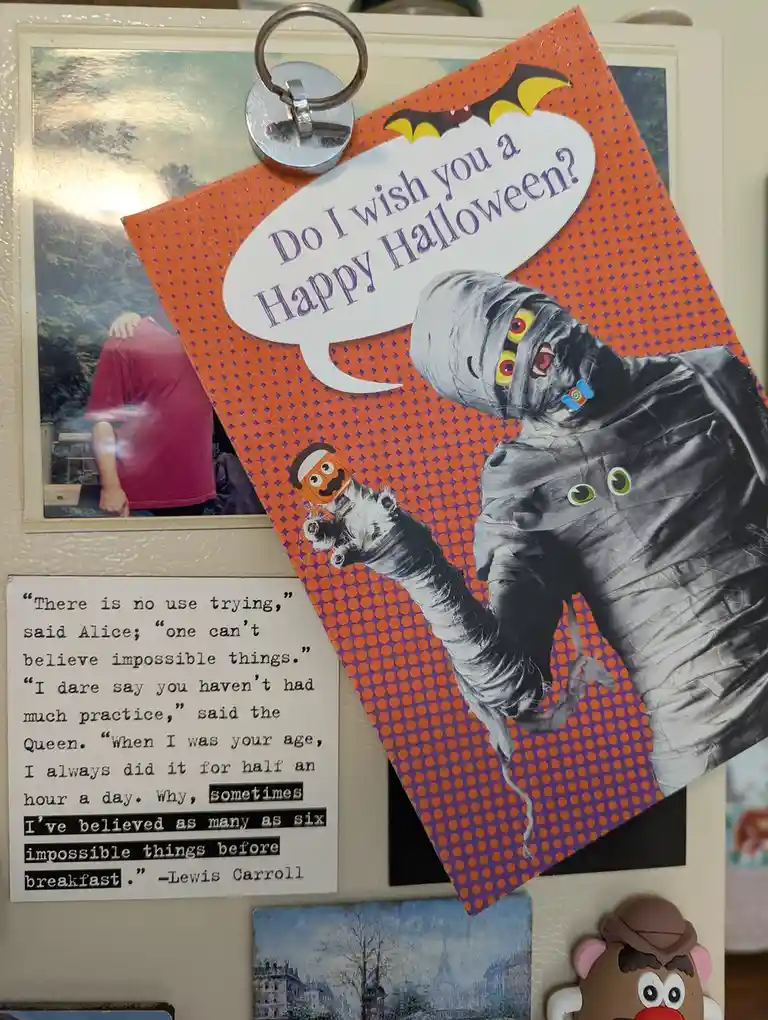 A Halloween greeting card featuring a cartoon mummy with googly eyes and a small pumpkin-headed hand holding a candy, asking…