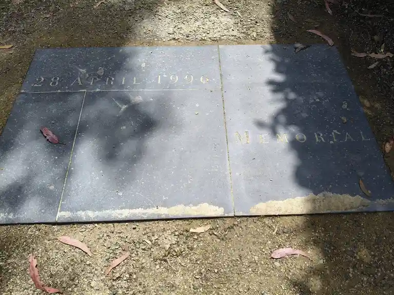 A close-up of a dark grey memorial plaque divided into three sections, engraved with '28 APRIL 1996' on the top left…
